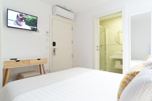 a white bedroom with a bed and a tv on the wall at Alojamento da Vila in Valença