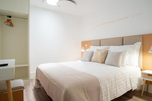 a bedroom with a large bed with white sheets and pillows at Alojamento da Vila in Valença