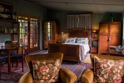 um quarto com uma cama, uma mesa e cadeiras em Woodcutters Forest Cottages em Knysna