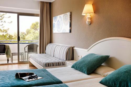 Habitación de hotel con cama y sofá en Hotel Mariant, en S'Illot