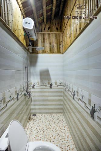 a bathroom with a white toilet and a shower at Tam Coc River View Homestay in Ninh Binh