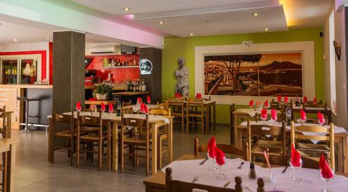 a restaurant with tables and chairs with red napkins on them at Hôtel Les Italiens in Biscarrosse