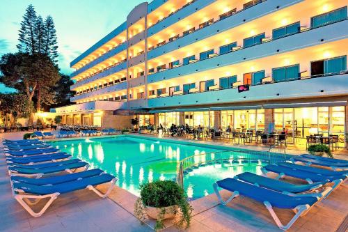una piscina de hotel con tumbonas frente a un edificio en Hotel Mariant, en S'Illot