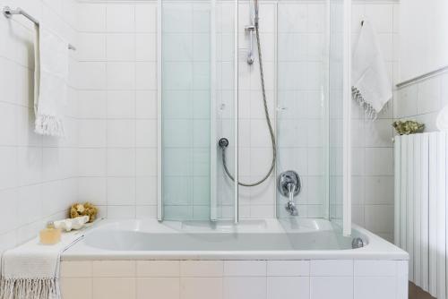 Un baño blanco con bañera y ducha. en Palazzo Garibaldi - MyHomeInComo, en Como