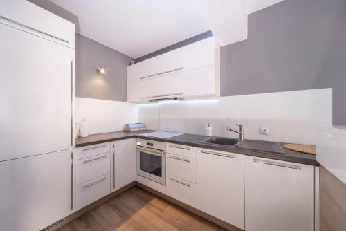 a white kitchen with white cabinets and a sink at Apartments Secret Garden Sopot by Renters in Sopot