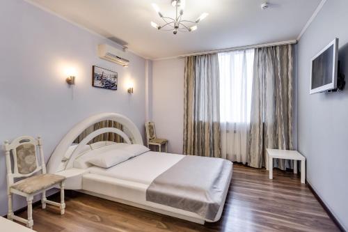 a white bedroom with a bed and a window at Venecia Hotel in Rostov on Don