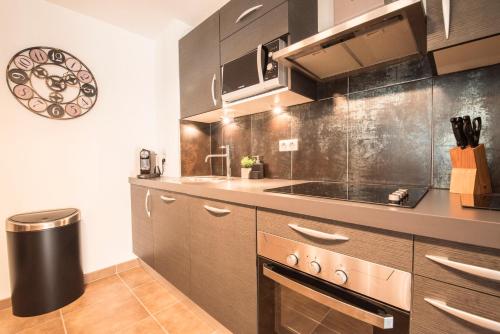 a kitchen with brown cabinets and a clock on the wall at T4 8 personnes de grand standing classé 4 étoiles en plein centre de Saint Lary Soulan in Saint-Lary-Soulan