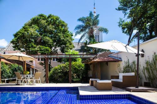 a pool with chairs and umbrellas next to a house at Pousada Villa Magnolia in São João del Rei