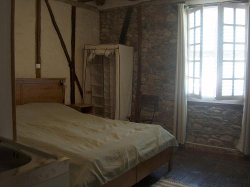 een slaapkamer met een bed, een raam en een wastafel bij Le Petit Chat in Beaulieu-sur-Dordogne