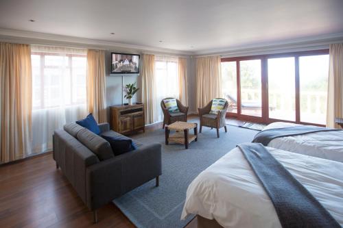 a bedroom with a bed and a couch and chairs at The Tuscany Guesthouse in Wilderness