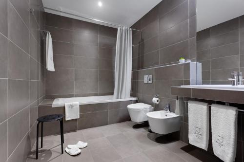 a bathroom with a white toilet and a sink at Rossio Hotel in Portalegre