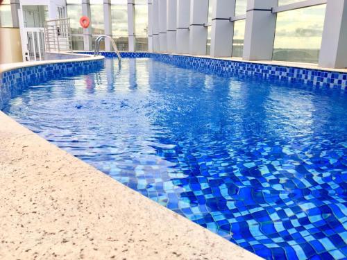 una piscina con azulejos azules en un edificio en Flat Fusion Setor Hoteleiro Norte com serviço diário de limpeza, en Brasilia