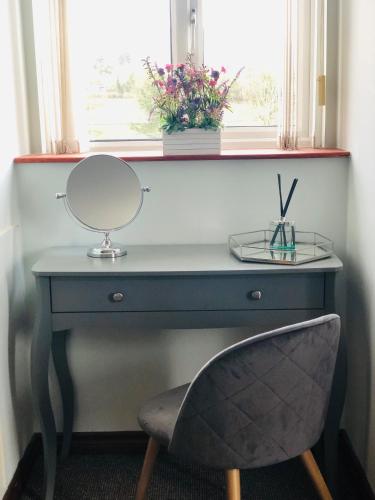 a desk with a mirror and a chair in front of a window at Muff Village Bed & Breakfast in Muff