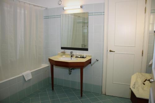 a bathroom with a sink and a mirror and a tub at Thermae Palace in Ostend