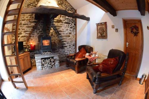 a living room with two chairs and a stone fireplace at La Paisière in Montaudin