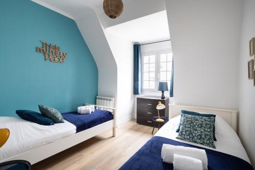 a bedroom with two beds and a blue wall at L'Anémone in Saint Malo