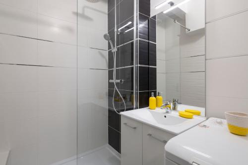 uma casa de banho branca com um chuveiro e um lavatório. em L'Anémone em Saint Malo