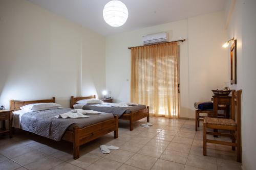 1 dormitorio con 2 camas, mesa y ventana en Hill of Calm, en Triopetra