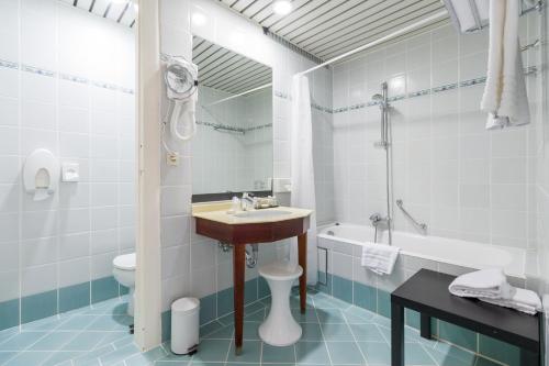 a bathroom with a sink and a toilet and a tub at Thermae Palace in Ostend
