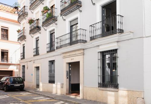 a white building with balconies and a car parked on a street at ELEVEN Real de la Carretería, by Homing U in Seville