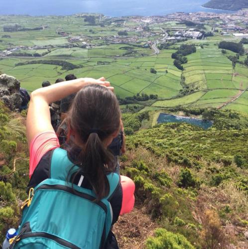 a woman with a backpack standing on top of a mountain at Vale Dos Milhafres in Angra do Heroísmo