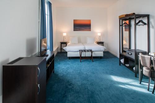 a bedroom with a bed and a dresser and a television at Thermae Palace in Ostend
