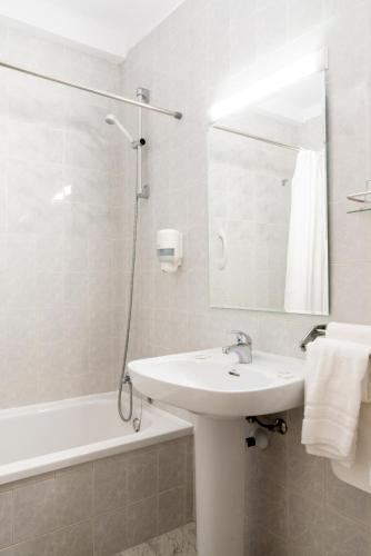 a bathroom with a sink and a tub and a mirror at Hotel Riutort in El Arenal