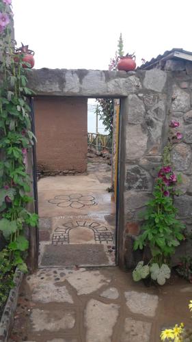 an open door into a courtyard with flowers at Amantani Lodge in Amantani