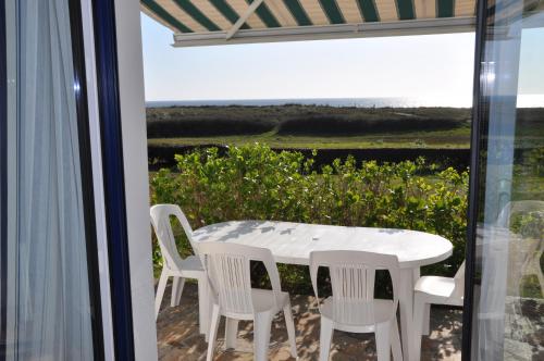 une table et des chaises sur un balcon avec vue sur l'océan dans l'établissement Maison de vacances au bord de la plage, à Trégunc