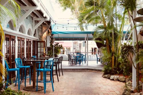 un restaurante con sillas azules, mesas y palmeras en The Casablanca Hotel, en Key West