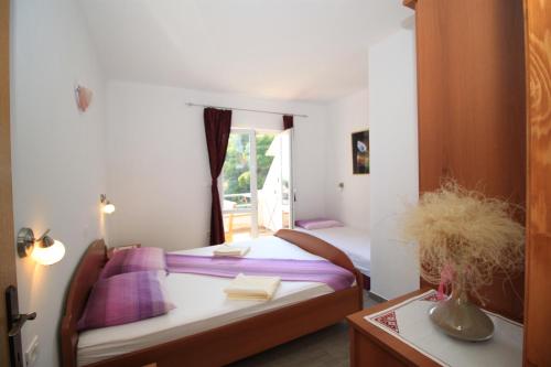 a bedroom with two beds with purple pillows and a window at Apartments Pitarević in Saplunara