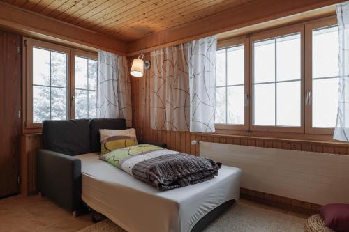 um quarto com uma cama num quarto com janelas em Ferienwohnung Sunnehöckli em Sattel