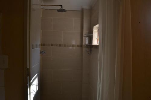 a bathroom with a shower with a glass door at Heloise Home Stay in Oudtshoorn