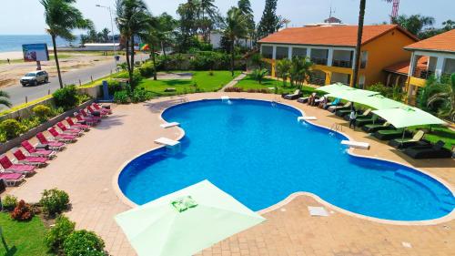 an overhead view of a swimming pool with chairs and umbrellas at Hotel Palm Beach in Pointe-Noire