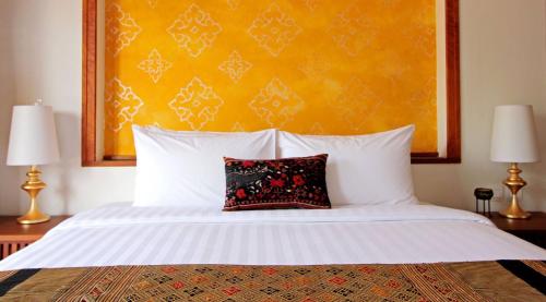 a bedroom with a white bed with a red pillow at Le Palais Juliana in Luang Prabang