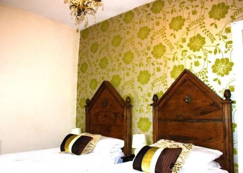two beds in a bedroom with green floral wallpaper at Ye Olde Nags Head in Castleton