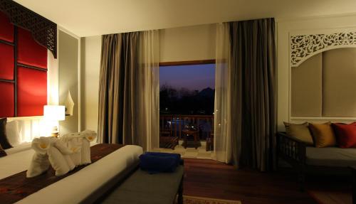 a hotel room with a bed and a window at Le Palais Juliana in Luang Prabang