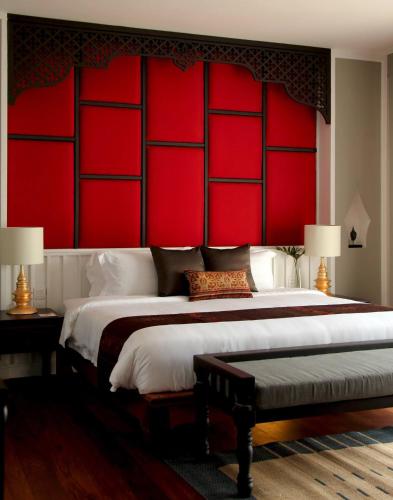 a bedroom with a large bed with red walls at Le Palais Juliana in Luang Prabang