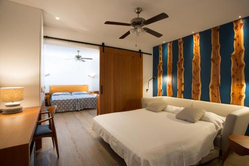 a bedroom with a bed and a desk with a ceiling fan at Hotel Ca Marí in Playa Migjorn