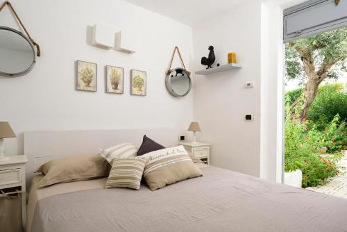 a white bedroom with a bed and a window at B&B Trullo Barbagiullo in Cisternino