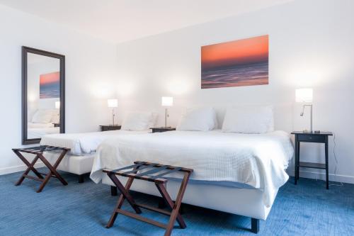 two beds in a room with two tables and a mirror at Thermae Palace in Ostend