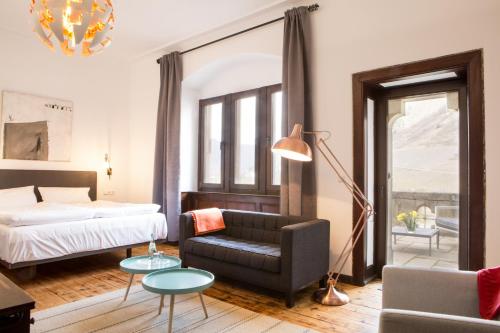 een slaapkamer met een bed, een bank en een stoel bij Hotel Villa Vie Cochem in Cochem