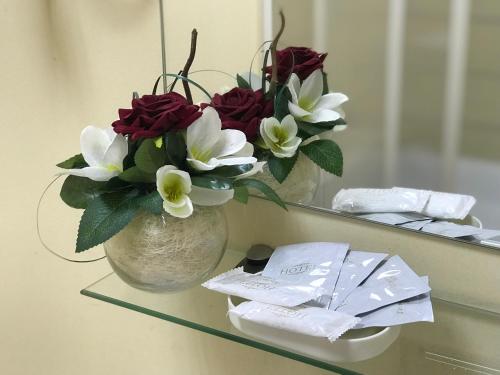 eine Vase mit roten und weißen Blumen auf einem Spiegel in der Unterkunft Davidov Inn in Kasan