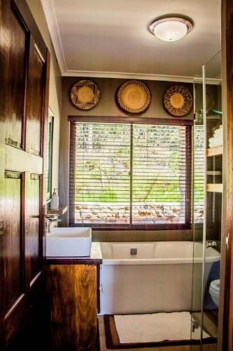 a bathroom with a tub and a sink and a window at African Safari Lodge in Grahamstown