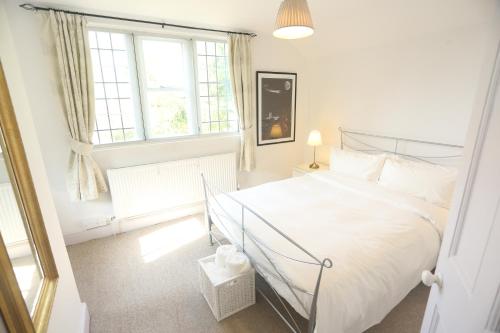 a white bedroom with a bed and a window at Entire Victorian Lodge in a privately gated estate with secure parking for two cars and a newly refurbished bathroom in Bath