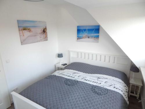 sypialnia z łóżkiem i 2 zdjęciami na ścianie w obiekcie Haus SMEELWAI 21 w mieście Westerland