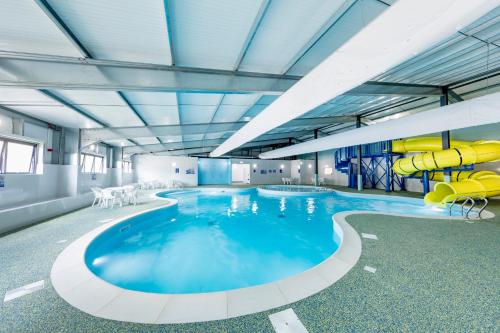 een groot zwembad met een glijbaan in een gebouw bij Camping Pods, Birchington Vale Holiday Park in Birchington