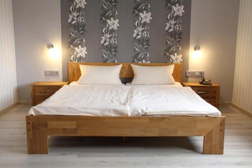 a bedroom with a wooden bed with white sheets at Gästehaus Loehnert GmbH in Coburg