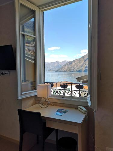 a desk with a window with a view of the water at Hotel Helvetia in Lezzeno