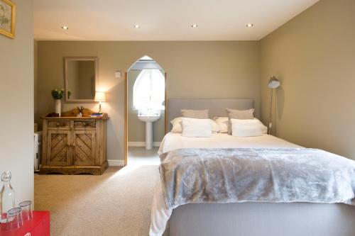 a bedroom with a large bed and a mirror at Grooms Cottage in Weedon Bec